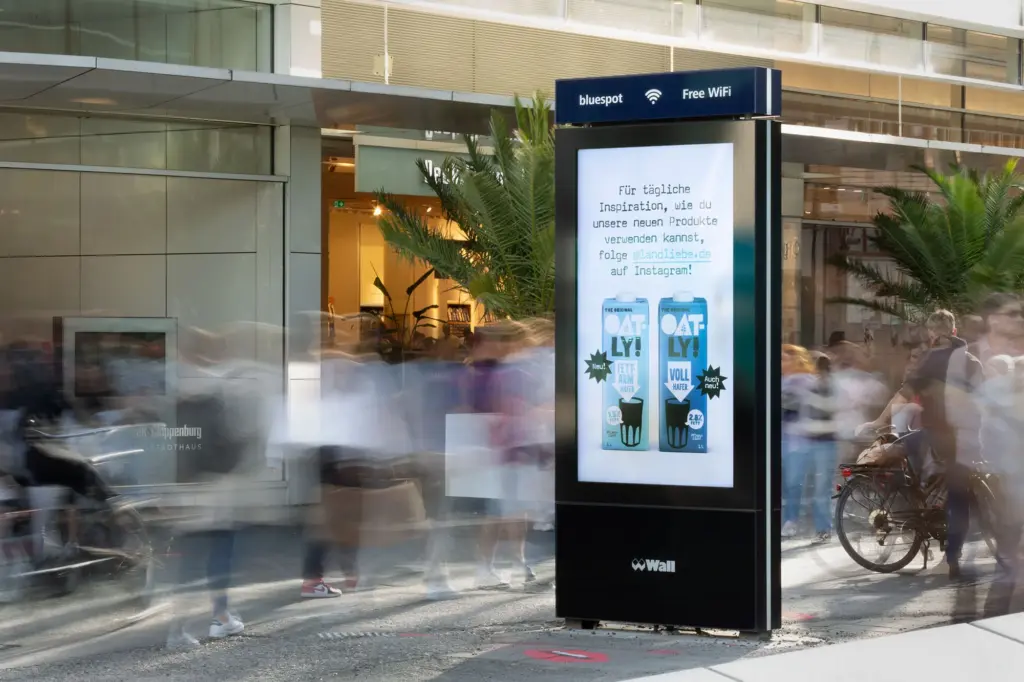 Digitale Werbestele mit Passanten in Bewegungsunschärfe